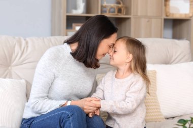 Güzel anne ve tatlı küçük kızı evdeki kanepede oturuyor.