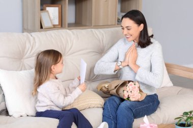 Şirin küçük kızı, güzel annesini hediye kartı ve bir buket gülle karşılıyor. Anneler Günün kutlu olsun.