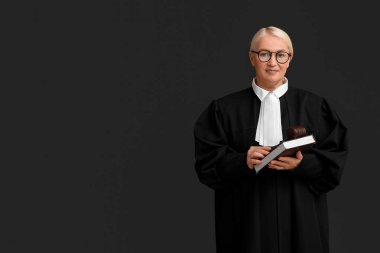 Siyah arka planda kitap ve tokmakla olgun kadın yargıç.