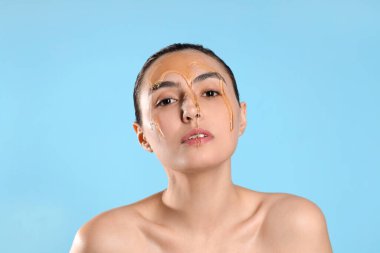 Yüzüne bal damlatan güzel bir genç kadın mavi arka planda, yakın plan