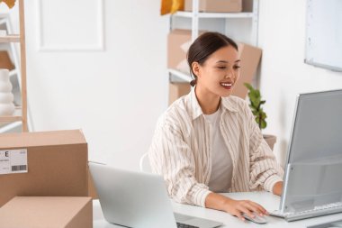 Female Asian seller working with computer in warehouse store