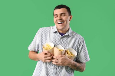 Yeşil arka planda patates kızartması olan genç adam.