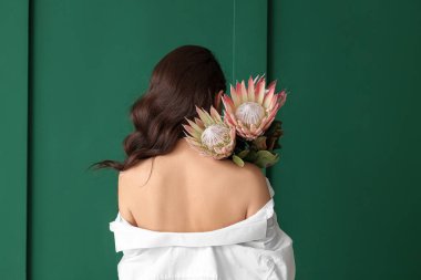 Yeşil arka planda güzel protea çiçekleri olan genç bir kadın.