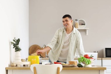 Genç adam mutfakta sandviçler için çıtır çıtır tost yapıyor.