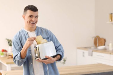 Genç adam mutfakta çıtır tost makinesiyle modern tost makinesini tutuyor.