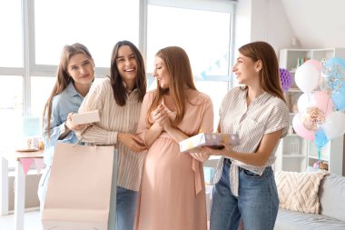 Bebek partisinde arkadaşlarından hediye alan hamile bir kadın.