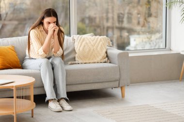 Evdeki kanepede dua eden güzel bir kadın.