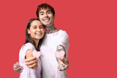 Kırmızı arka planda kağıt kalpli genç çift