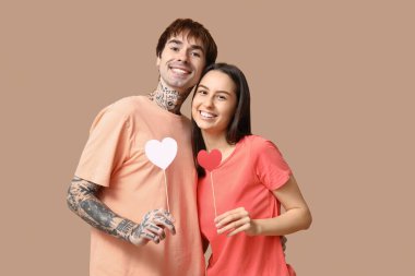 Bej arka planda kağıt kalpli genç çift