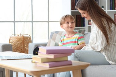 Küçük çocuk ve annesi evdeki kanepede kitap okuyorlar.