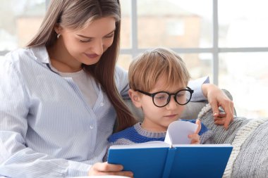 Mother with her son reading book at home, closeup