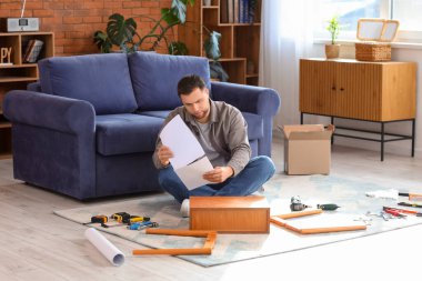 Young man with manual assembling table at home
