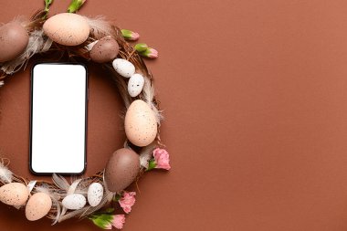 Renkli arka planda güzel Paskalya çelengi olan modern cep telefonu.