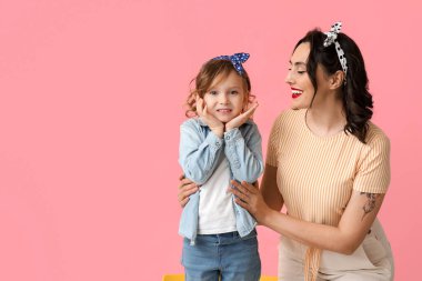 Pembe arka planda güzel bir kadın ve kızı.