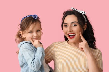 Pembe arka planda güzel bir kadın ve kızı.