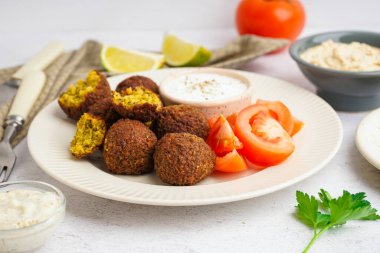Hafif arka planda nefis falafel köfteli, soslu ve domatesli tabak, yakın plan.