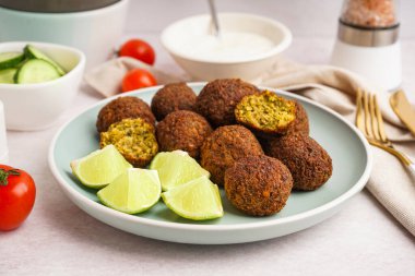 Nefis falafel köfteli tabak, arka planda limon ve domates, yakın plan.