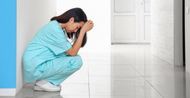 Depressed female Asian nurse in hallway of clinic