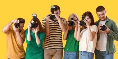 Sarı arka planda bir grup genç fotoğrafçı
