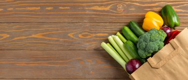 Tahta zemin üzerinde taze sebzeler ve metin için yeri olan kağıt alışveriş torbası.