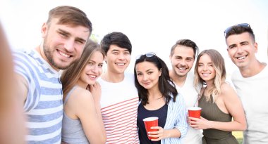 Group of attractive young friends taking selfie outdoors