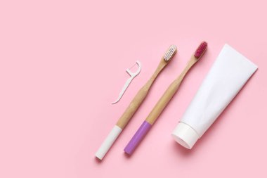 Diş fırçaları, diş ipi kürdanı ve pembe arka planda diş macunu. Dünya Diş Hekimi Günü