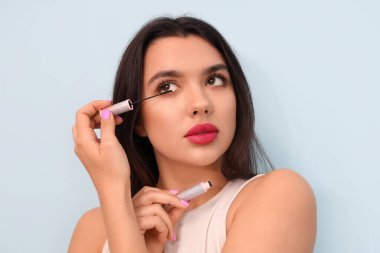 Mavi arka planda zarif maskarası olan güzel genç bir kadın.