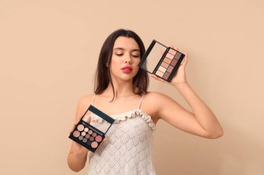 Bej arka planda şık göz falı paletleri olan güzel genç bir kadın.