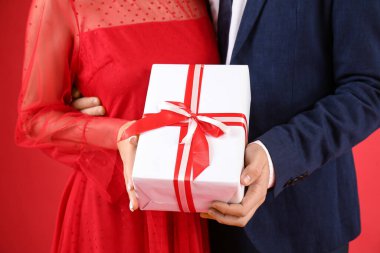Couple with gift for Valentine's day on red background