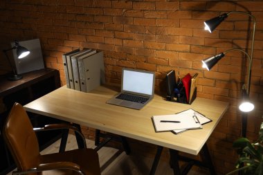 Karanlık ofis, iş yeri, boş laptop ve geceleri parlayan lambalar.