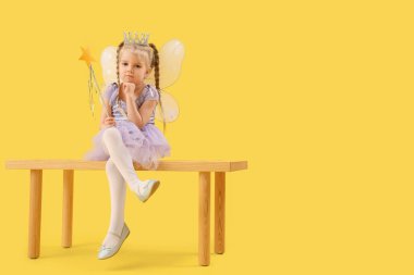 Sarı arka planda bankta oturan sevimli küçük peri.