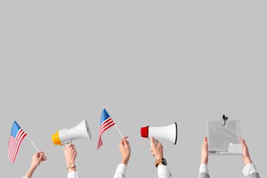 Eller oy sandığını tutuyor, beyaz arka planda Amerikan bayrakları ve megafonları var. Seçim kavramı