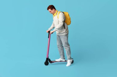 Mavi arka planda modern elektrikli scooter kullanan erkek öğrenci.