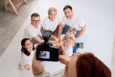 Erkek fotoğrafçı stüdyoda büyük bir ailenin fotoğrafını çekiyor.