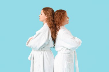 Mavi arka planda bornozlu mutlu kızıl kız kardeşler.