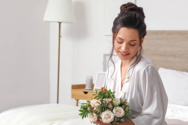 Yatak odasında düğün buketi olan genç gelin.