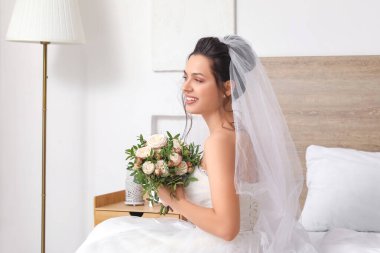 Gelin ve düğün buketi yatak odasında oturuyor.