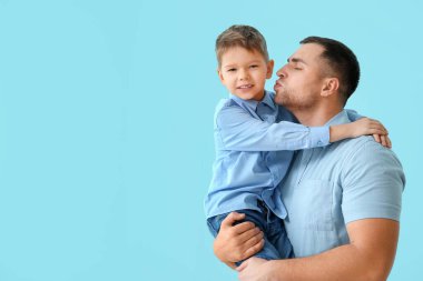 Mutlu baba mavi arka planda oğlunu öpüyor.