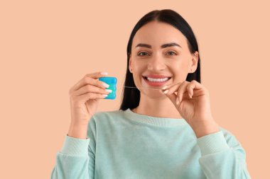 Bej arka planda diş ipi olan güzel, mutlu genç bir kadın.