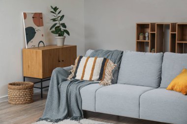 Stylish grey sofa with picture and houseplant in living room