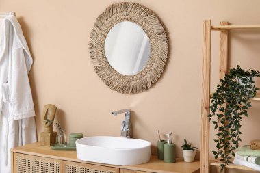 Banyoda kahverengi duvarın yanındaki tezgahta banyo malzemeleri olan modern lavabo.