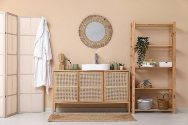 Banyoda kahverengi duvarın yanındaki tezgahta banyo malzemeleri olan modern lavabo.