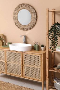 Banyoda kahverengi duvarın yanındaki tezgahta banyo malzemeleri olan modern lavabo.