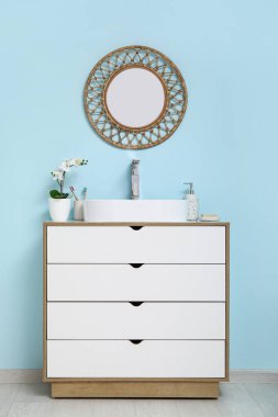 Banyoda mavi duvarın yanında banyo malzemeleri olan modern lavabo.