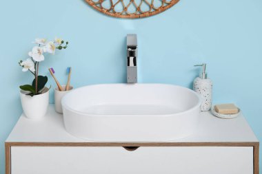 Banyoda mavi duvarın yanında banyo malzemeleri olan modern lavabo.