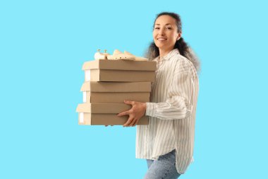 Female shoemaker with wooden shoe trees and boxes on blue background