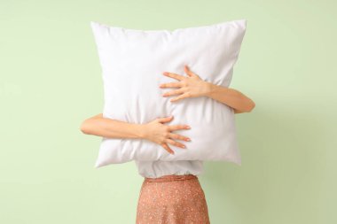 Woman holding white pillow on light background