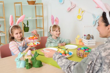 Little children in bunny ears with Easter eggs at family dinner