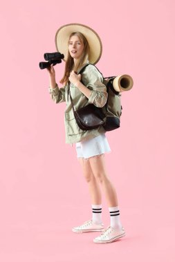 Pembe arka planda dürbünü olan kadın gezgin.