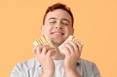Young happy man smiling and holding doner kebab on beige background